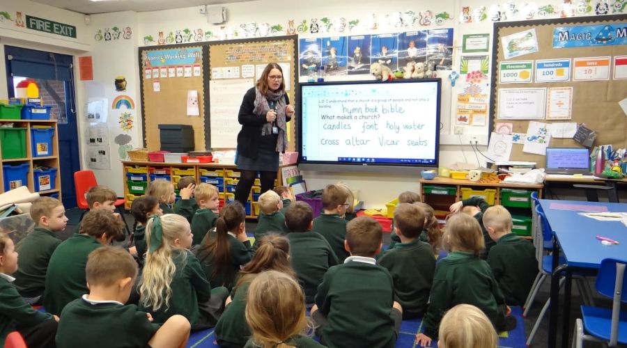 Teacher teach a students on interactive panel display in classrom