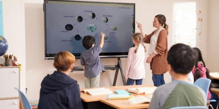 Teacher Teach a students on interactive flat panel display in classroom